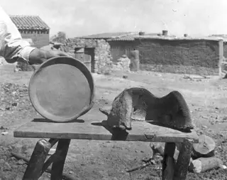 Round clay dish and a curved clay windbreak for an outdoor fire, on a wooden bench at Klirou