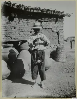 Rope-maker twisting net cord in front of a mud-brick farm wall at Klirou, farmstead A