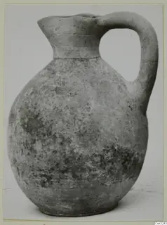 Pottery jug with a single loop handle and a flared neck, photographed against a plain background.