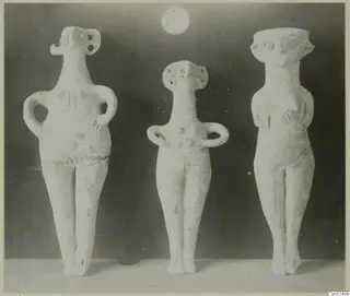 Three pale clay figurines standing side by side, from Katydhata