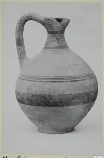 White Painted V jug with a single loop handle, a narrow neck and dark painted bands around the body