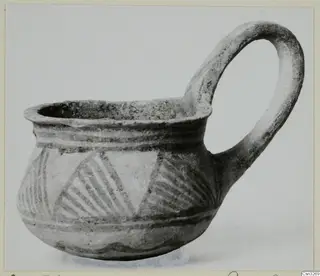 White Painted III-2 cup from Lapithos with a tall loop handle and hatched triangles on the body