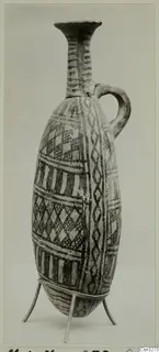 Pottery vessel with a single handle and painted geometric bands, shown on a three-legged metal stand