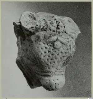 Terracotta minor plastic fragment with a pitted surface and a round knob, photographed against a grey background