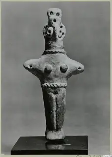 Clay figurine with a bird-like head and twisted rope bands, standing on a dark stand