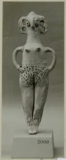 Terracotta idol figurine of a standing female figure with arms on hips and a dotted pattern on the lower body