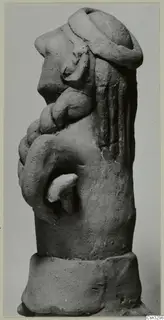 Terracotta figure in side view, with a rounded head, bent arm and thick ring-shaped base.