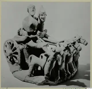 Terracotta model of a chariot with two standing figures, a spoked wheel and a team of horses