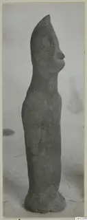 Terracotta figurine of a standing figure, seen in side profile against a plain backdrop