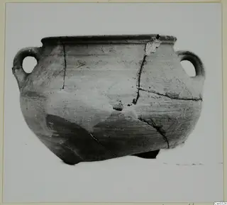 Round pottery vessel with a wide rim and two loop handles, photographed upright against a pale backdrop.