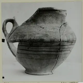Painted pottery vessel from Milia with a single loop handle, dark horizontal bands and a broken rim