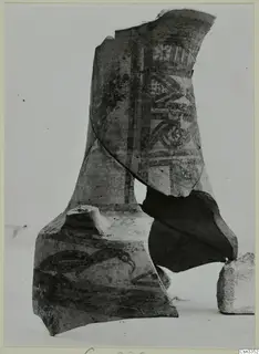 Painted pottery sherds with vertical bands, geometric panels and a curved motif, propped together on a pale surface