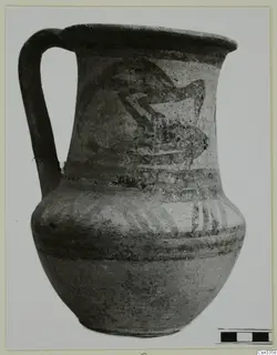 Wheel-made jug with a high loop handle and dark painted bands and motif on a pale body.