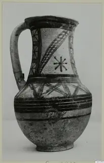 Painted jug with a strap handle, dark banded and cross-hatched decoration on a pale surface