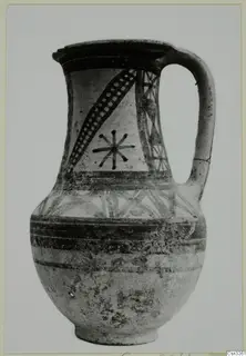 Painted pottery jug with a single loop handle, black bands and a star-like motif on a light ground.