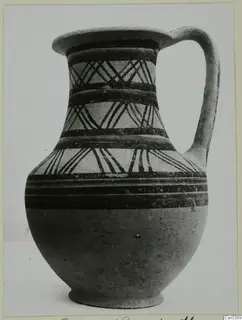 Bichrome wheel-made jug with a single handle, dark painted bands and diagonal patterns on a pale slip