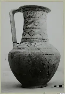 Wheel-made painted jug with a tall handle and banded decoration on the neck and body, shown against a plain background.