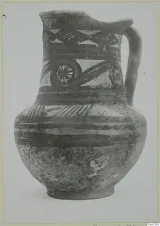 Painted pottery jug with a single loop handle, decorated with bands, triangles and a wheel-like motif.
