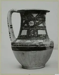 Painted wheel-made jug with a strap handle, dark geometric bands and a lattice panel on a pale ground.