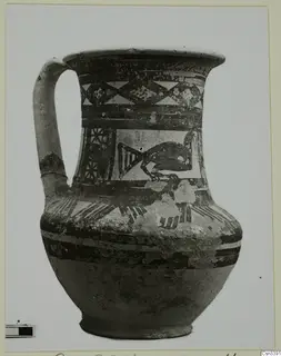 Painted jug with a single handle, bands and triangular patterns, and a dark bird-like motif on the body