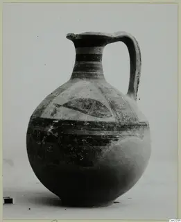 Bichrome wheel-made jug with a single handle, banded neck and a dark curved motif in a panel on the shoulder