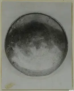 Shallow circular metal bowl seen from above, with a handwritten number label in blue ink on its inner surface