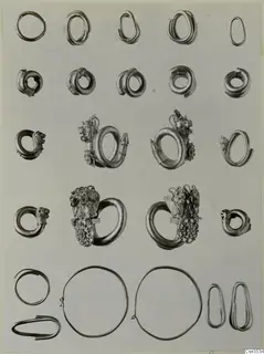 Plate of gold rings, bracelets and hoops laid out in rows, several with animal-head terminals and rosette ornament.