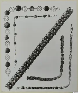 Several necklaces and a wide bracelet of metal beads, filigree discs and rosette ornaments, laid out on a pale background.