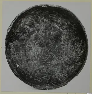 Circular bowl with engraved scenes of figures, animals and chariot-like shapes, photographed from above