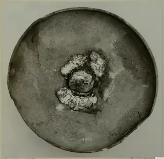 Shallow bowl seen from above, with decorated sherds and a rounded knob at its centre