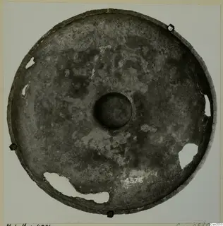 Shallow circular metal dish with a central boss, photographed from above on a mount card