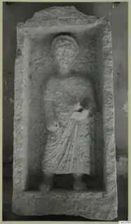 Carved stone relief of a standing figure in long drapery, set in a recessed panel, from Cyprus