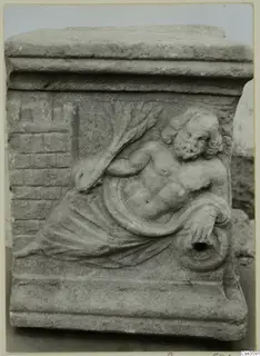 Carved relief of a reclining bearded figure on a stone block with a moulded top and base