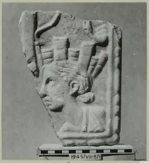Relief fragment of a stone plaque with a head in profile facing left and a tall, upright headdress