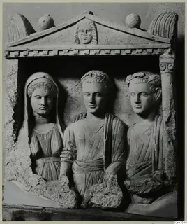Carved stone relief of three figures in a pedimented niche, a veiled woman on the left.