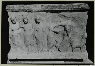 Stone relief block with four standing figures at left, a wheel and an animal at right
