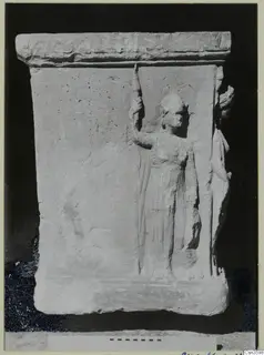 Relief on a limestone slab showing a standing figure in a long garment, raising a tall staff in one hand