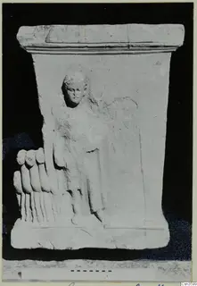 Limestone relief block with a standing figure in relief and a row of toe-like forms projecting at the left