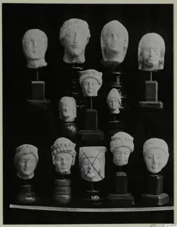 Limestone minor plastic: about a dozen carved stone heads on stands, shown in rows against a black background