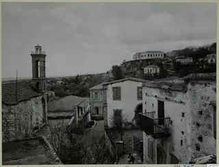 Village street at Lapithos with a church bell tower, whitewashed and stone houses, and bare trees.