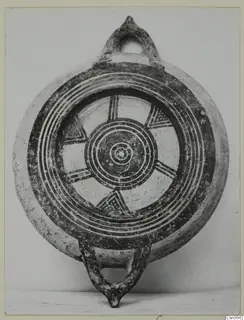 Round painted pottery vessel with two loop handles, dark concentric rings and triangular motifs on a light clay ground