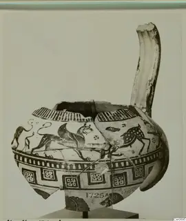 Reconstructed painted pottery vessel with a tall curved spout, decorated with animal friezes and geometric panels.