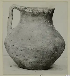 Pottery jug with a single loop handle, seen from the side against a plain light background