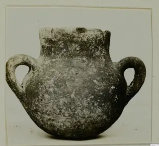 Coarse ware two-handled pot with a short neck and rounded body, photographed against a plain background.