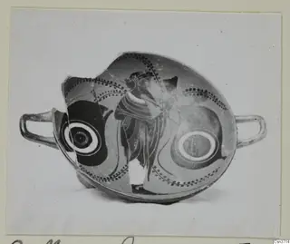 Fragmentary black-figured pottery cup with two handles, a standing figure and dotted bands