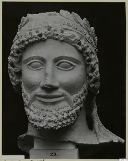 Cypro-Greek II limestone head of a bearded man from Arsos, shown on a plinth against a black background