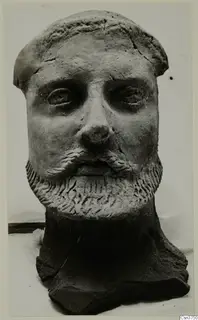 Sculpted bearded head from Mersinaki, shown frontally, with the neck broken off