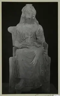 Seated female figurine on a chair with curved arms, shown against a black background