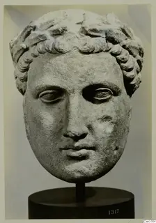 Marble head of a youth with a wreath of curled hair, mounted on a dark stand