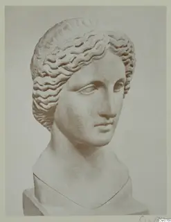 Head and bust of a female statue carved in stone, with wavy hair drawn back from the face